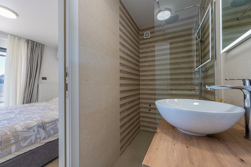 Modernes Badezimmer mit elegantem Waschbecken, Armatur und Glasdusche.