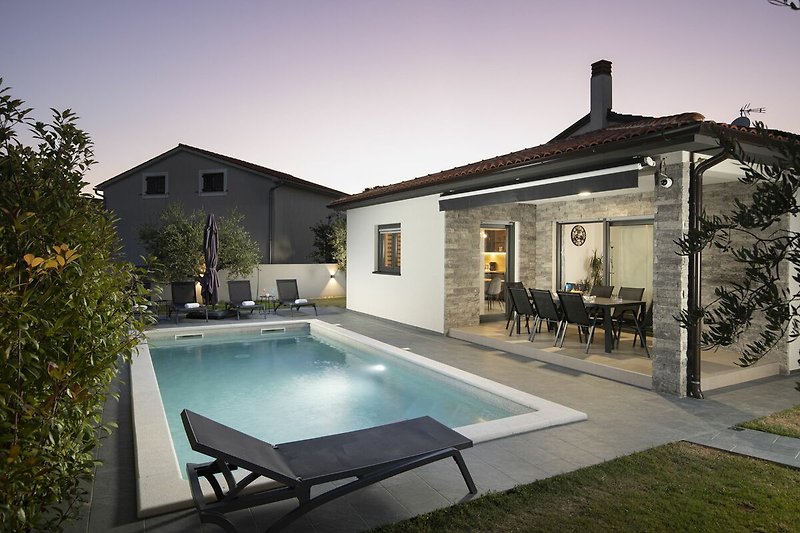 Villa mit Pool, Patio und Gartenmöbeln.