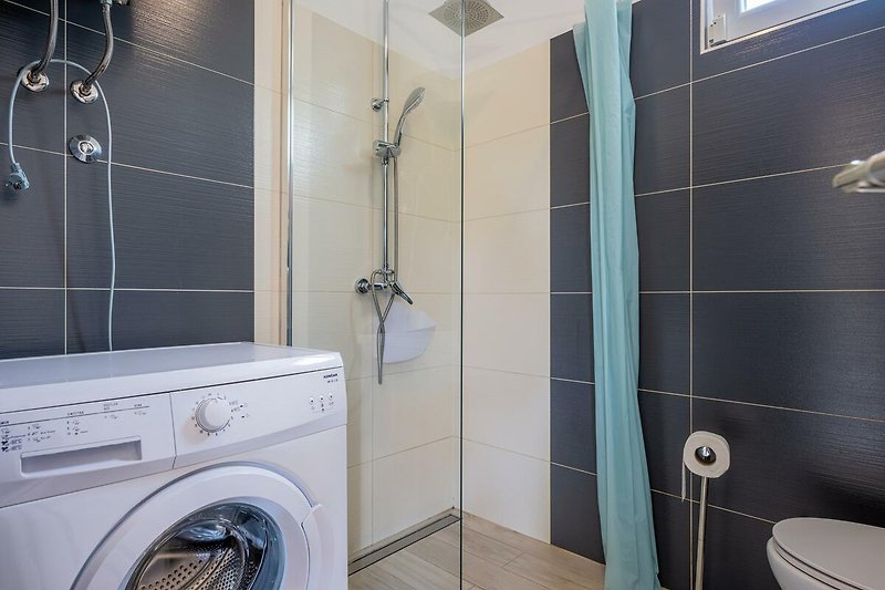 Gemütliches Badezimmer mit moderner Dusche und Waschmaschine.