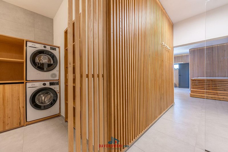 Modernes Waschzimmer mit Waschmaschine, Trockner, Holzboden und Audioausstattung.