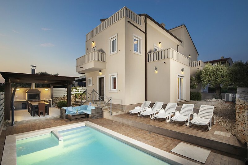 Villa mit Pool, Balkon und stilvoller Außenbeleuchtung.