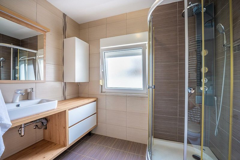 Entspannen Sie in diesem stilvollen Badezimmer mit hochwertigen Armaturen und genießen Sie den Komfort.