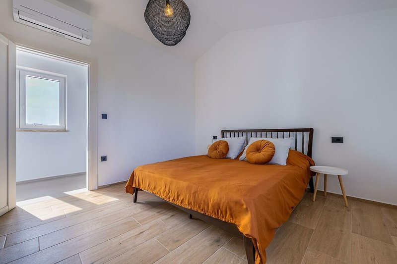 Schlafzimmer mit Holzmöbeln, gemütlichem Bett und Fensterblick.