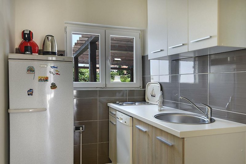 Moderne Küche mit Gasofen, Aluminium-Spüle und Holzschrank.