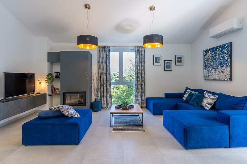 Ein stilvoll eingerichtetes Wohnzimmer mit blauem Sofa und warmem Licht.