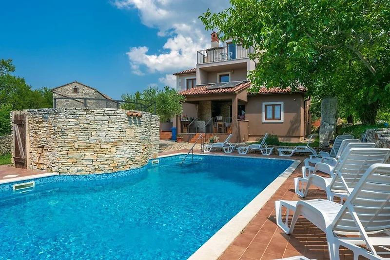 Privater Pool mit Liegestühlen, umgeben von grüner Landschaft und Bäumen.