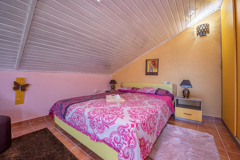 Gemütliches Schlafzimmer mit lila Bett und stilvoller Dekoration.