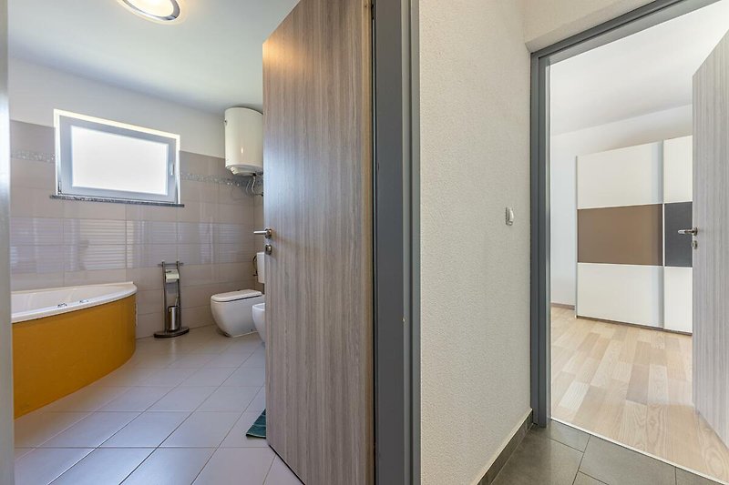 Gemütliches Badezimmer mit Holzboden, Fliesen und modernen Armaturen.
