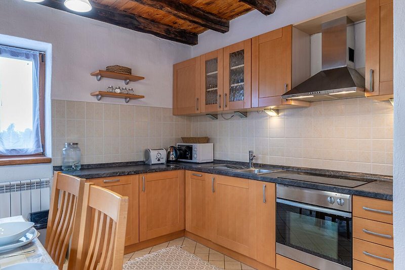 Schöne Küche mit Holzmöbeln, Granit-Arbeitsplatte und modernen Geräten.