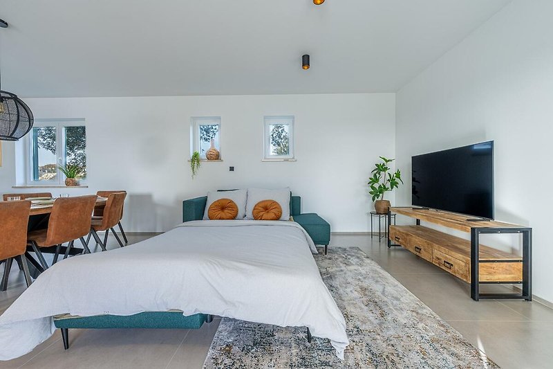 Wohnzimmer mit bequemen Möbeln, Holzboden und Fernseher.