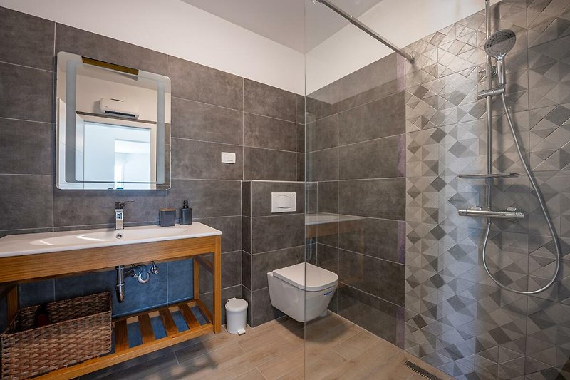Genießen Sie die moderne Badezimmerausstattung und entspannen Sie unter der stilvollen Dusche. Perfekt für einen erholsamen Urlaub!