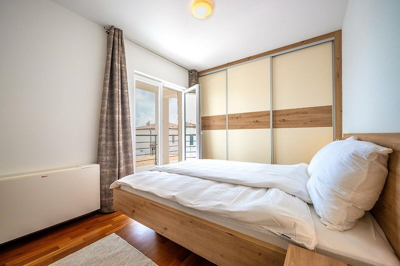 Verbringen Sie Ihren Urlaub in diesem komfortablen Schlafzimmer mit stilvollem Holzmobiliar und gemütlichem Bett. Genießen Sie die schöne Aussicht aus dem Fenster.