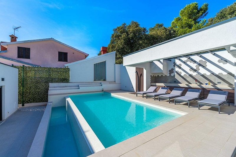 Luxuriöses Haus am Wasser mit Pool und Sonnenliegen.
