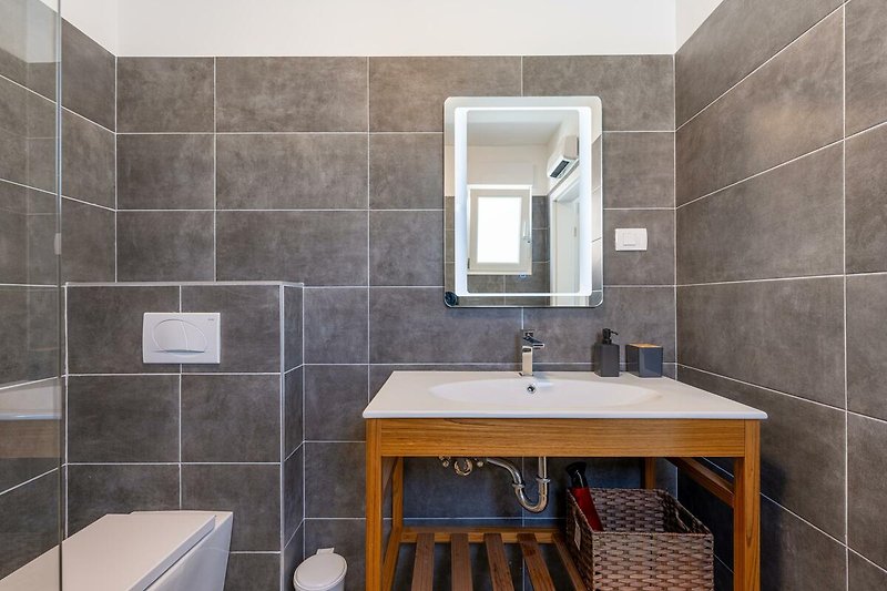 Gemütliches Badezimmer mit stilvoller Ausstattung. Entspannen Sie unter der stilvollen Dusche und genießen Sie den Komfort. Perfekt für einen erholsamen Urlaub!