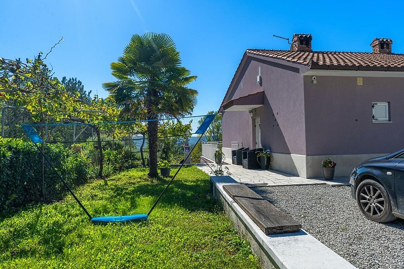 Gemütliches Haus mit blauem Dach, grünem Garten und asphaltierter Straße.