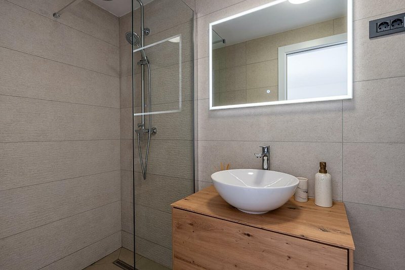 Modernes Badezimmer mit elegantem Waschbecken, Armatur und Glasdusche.