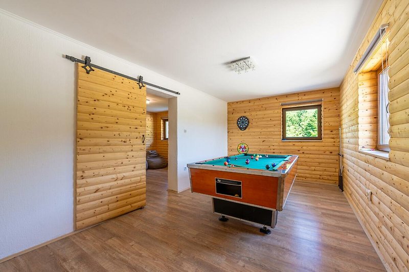 Gemütlicher Billardraum mit Holzboden und Pool. Perfekt zum Spielen und Entspannen.