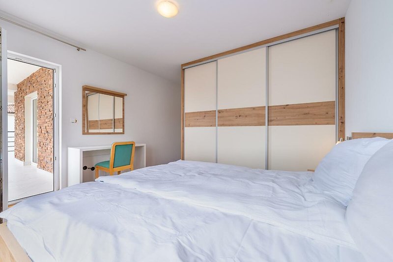 Entspannen Sie in diesem komfortablen Schlafzimmer mit stilvollem Holzmobiliar und gemütlicher Beleuchtung.