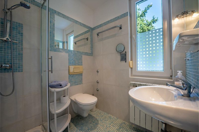 Badezimmer mit lila und blauen Fliesen, Spiegel, Waschbecken und Wasserhahn.