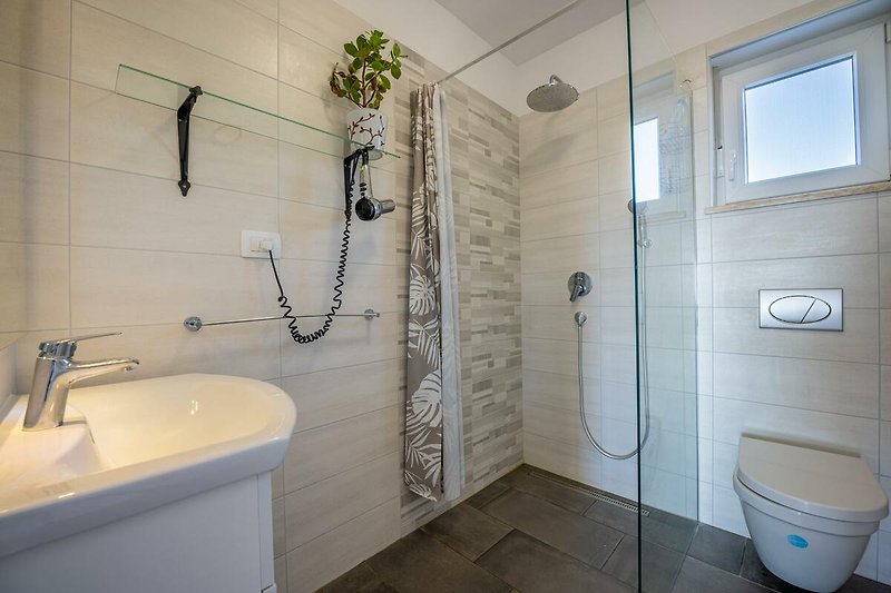 Schönes Badezimmer mit stilvoller Einrichtung und rechteckigem Glaswaschbecken.