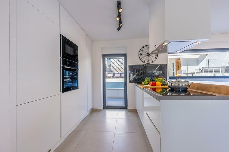 Küche mit moderner Einrichtung, Fenster und Arbeitsplatte.
