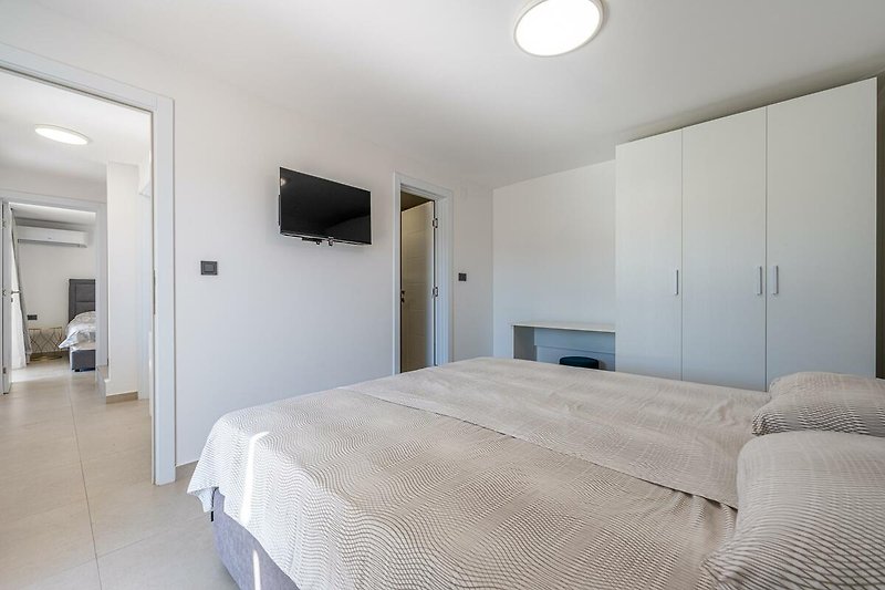 Modernes Schlafzimmer mit stilvollem Bett, elegantem Holz und gemütlicher Beleuchtung.