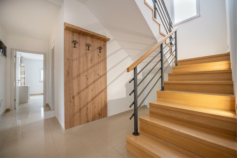 Willkommen in diesem geräumigen Ferienhaus mit elegantem Holzdesign und stilvoller Treppe. Erkunden Sie die schöne Architektur und genießen Sie den Luxus.