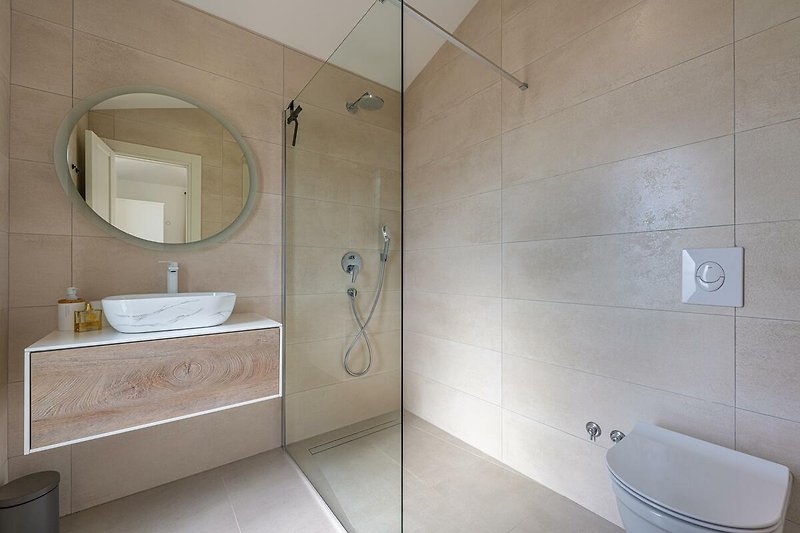 Modernes Badezimmer mit Dusche, Spiegel und Keramik.
