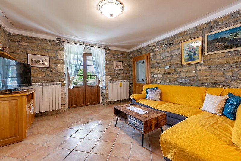 Gemütliches Wohnzimmer mit Holzmöbeln und gelber Couch.