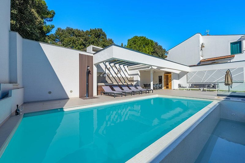 Luxuriöses Ferienhaus mit Pool und Blick auf den blauen Himmel.