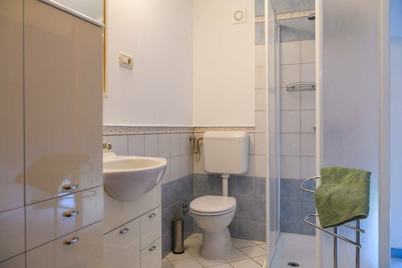 Schönes Badezimmer mit lila Vorhang, Holzboden und Spiegel.
