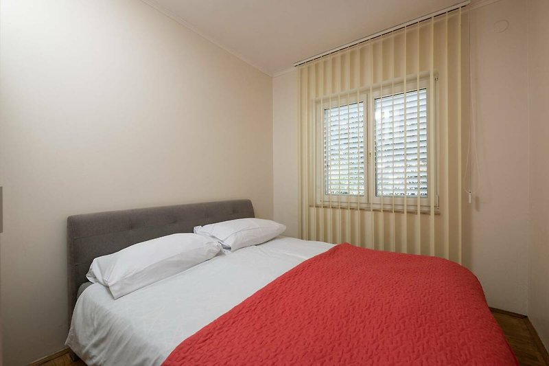 Gemütliches Schlafzimmer mit Holzbett und stilvoller Fensterdekoration.