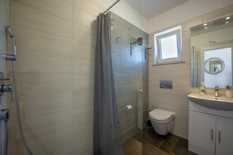 Schönes Badezimmer mit lila Dusche, Spiegel und Holzboden.