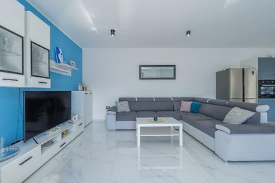 Modernes Wohnzimmer mit grauem Sofa, Tisch, Regal, Fernseher und Fenster.