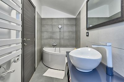 Modernes Badezimmer mit lila Akzenten, Spiegel, Waschbecken und Badewanne.