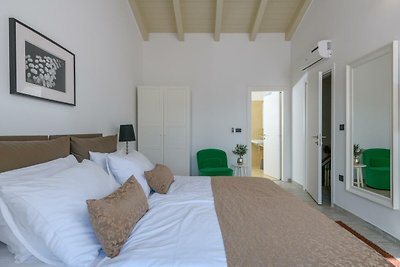 Modernes Schlafzimmer mit stilvollem Bett, dekorativer Beleuchtung und Bilderrahmen.