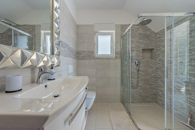 Modernes Badezimmer mit Dusche, Fenster, Waschbecken und Armaturen.