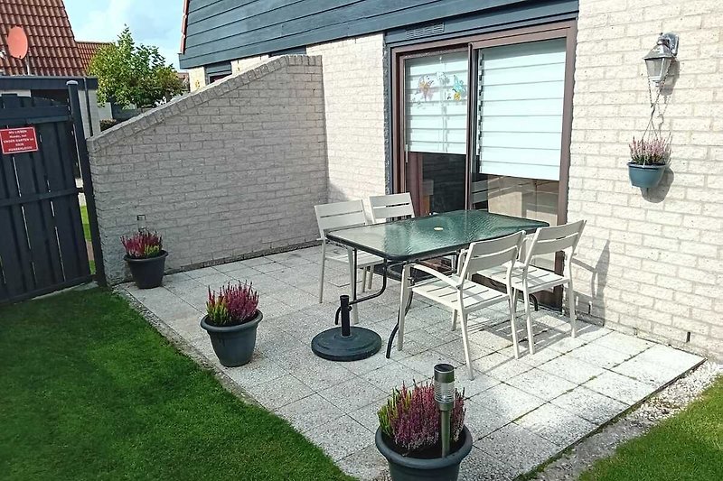 Schöne Terrasse mit Tisch, Stühlen und Sonnenschirm.