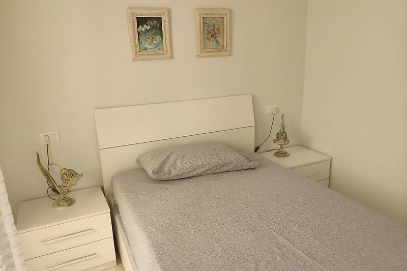 Camera da letto con letto in legno, arredamento confortevole e quadro artistico.