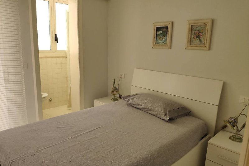 Camera da letto con letto in legno, arredamento confortevole e finestra luminosa.