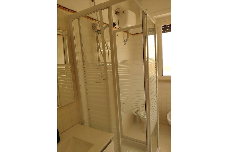 Modern bathroom with glass shower door, nickel fixtures, and ceramic tiles. Refreshing design.