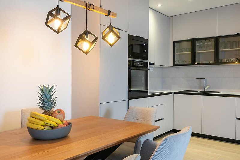 Moderne Küche mit Holzmöbeln, Stühlen und stilvoller Beleuchtung.