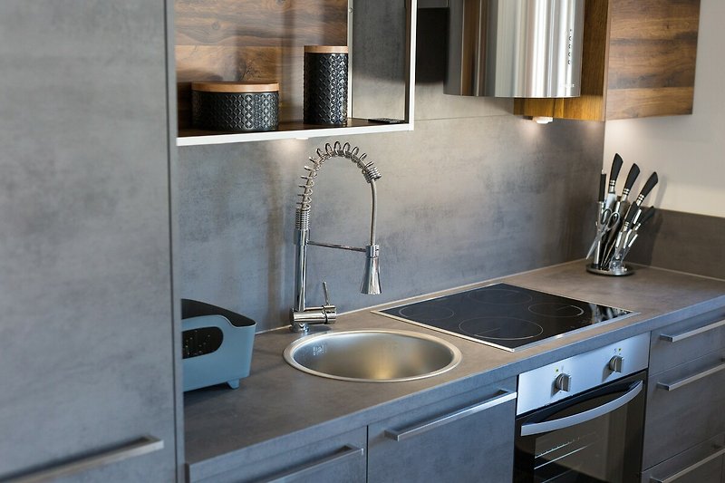 Moderne Küche mit Granit-Arbeitsplatte, Edelstahl-Spüle und Holzboden.