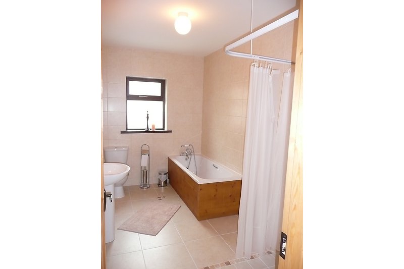 Gemütliches Badezimmer mit lila Badewanne und modernem Waschbecken.