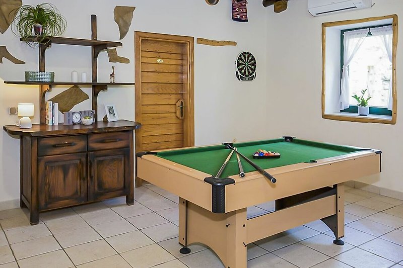 Wooden pool room with comfortable furniture and sports equipment.