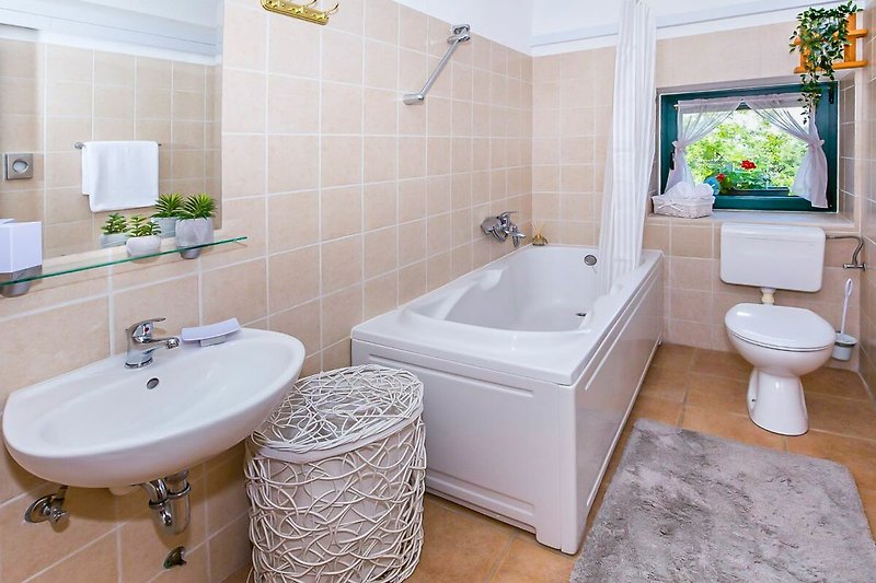 Sanitärausstattung im Badezimmer mit Badewanne, Waschbecken und Spiegel.