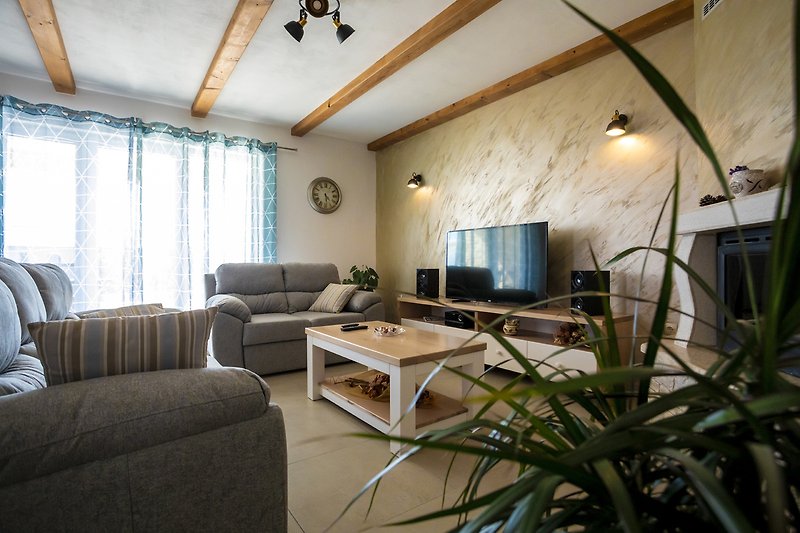 Wohnzimmer mit bequemer Couch, Tisch, Lampe und Pflanze.