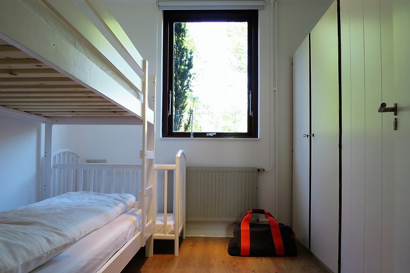 Sypialnia z łóżkiem piętrowym i łóżeczkiem dla dziecka.