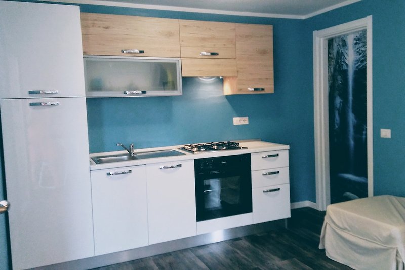 Moderne Küche mit Holzmöbeln, blauer Wand und Edelstahlgeräten.