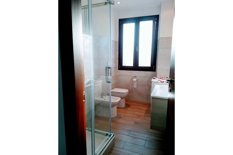 Modernes Badezimmer mit Glasdusche, Waschbecken und Spiegel.